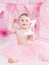 Portrait of cute adorable Caucasian baby girl with blue eyes in pink tutu skirt celebrating her first birthday with gourmet cake