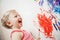 Portrait of cute adorable white Caucasian little boy girl playing and painting with paints on wall in bathroom