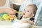 Portrait of cute adorably baby boy sitting in chair and eating f