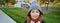 Portrait of cute asian girl in hat and scarf, walks around town in chilly spring weather, smiles and looks happy, sits