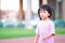 Portrait of cute Asian girl looks at the camera while jogging at the stadium. Child smiled slightly. Children wear pink t-shirts.