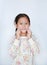 Portrait of cute asian little girl touch fingers on cheek and looking cameara over white background