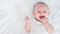 Portrait of cute asian newborn baby lying play on white bed look at camera with laughing smile happy face.