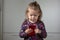 Portrait of cute and attractive child looking at mobile phone and holding it in hands