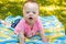 Portrait of Cute baby boy with Down syndrome lying on blanket in summer day on nature