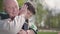 Portrait cute bald mature man sitting in the park on the bench reading the book. Adorable little boy hugging him from