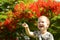 Portrait of a cute blond boy. A 5-year-old child laughs in front of a blooming Delonix regia. Place for text. Emotions