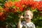 Portrait of a cute blond boy. A 5-year-old child laughs in front of a blooming Delonix regia. Place for text. Emotions