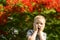 Portrait of a cute blond boy. A 5-year-old child laughs in front of a blooming Delonix regia. Place for text. Emotions