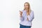 Portrait of cute blond girl laughing over something funny, pointing finger at hilarious thing and chuckle, standing over