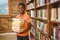 Portrait of cute boy carrying books in library