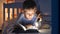 Portrait of cute boy in pajamas holding flashlight and reading interesting book. Children education, development, secrecy, privacy