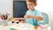 Portrait of cute boy pouring drawing brush in colorful paint and making beautiful picture. Creative child doing art