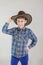 Portrait of cute Caucasian boy, elementary school student in cowboy hat on grey background . child aged 7 years first grader.