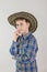 Portrait of cute Caucasian boy, elementary school student in cowboy hat on grey background . child aged 7 years first grader.