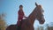 Portrait of a cute Caucasian female equestrian in pink clothes and horse riding helmet sitting in sunlight on the