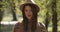 Portrait of cute Caucasian girl in brown hat in autumn park looking at camera and smiling. Pretty European woman closing