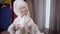 Portrait of cute caucasian girl in white bathrobe and hair towel singing at home. Joyful child using shampoo bottle