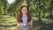 Portrait of cute Caucasian redhead teenage girl blowing cake candle on birthday in park smiling looking at camera. Happy