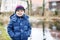 Portrait of cute caucasian toddler boy in warm clothes on cold d