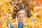 Portrait of a cute charming little girl standing in autumn park in the rain. The child stretched out his hands and collects the