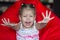 Portrait of cute child stretching hands forward sitting on red armchair pear