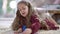 Portrait of cute confident girl drawing picture lying on carpet at home. Pretty charming Caucasian child enjoying