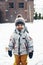 Portrait of a cute contented todler boy in winter clothes outdoors in the snow. Winter time, winter fun, happy childhood. Vertical