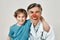 Portrait of cute excited little boy hugging with cheerful male pediatrician with clown nose. They are looking at camera