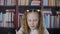 Portrait of cute focused schoolgirl holding pen and writing in classroom