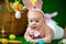 Portrait of a cute funny baby dressed in Easter bunny ears with eggs