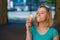 Portrait of a cute girl in a green dress is walking outside and eating dessert. Beautiful blonde enjoying a cone with