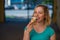 Portrait of a cute girl in a green dress is walking outside and eating dessert. Beautiful blonde enjoying a cone with ice cream on