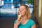 Portrait of a cute girl in a green dress is walking outside and eating dessert. Beautiful blonde enjoying a cone with ice cream on