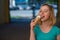 Portrait of a cute girl in a green dress is walking outside and eating dessert. Beautiful blonde enjoying a cone with ice cream on