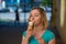 Portrait of a cute girl in a green dress is walking outside and eating dessert. Beautiful blonde enjoying a cone with ice cream on