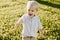 Portrait of Cute Handsome Blond Little Kid Boy in Colorful Striped Button Down Shirt Walking Outside in the Grass Watching the Sun