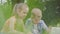 Portrait of a cute handsome boy and pretty girl with long hair waving hands in the camera of a laptop in the park