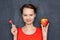 Portrait of cute happy girl holding apple and lollipop in hands
