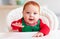 Portrait of cute infant baby boy in elf costume sitting in highchair