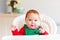 Portrait of cute infant baby boy in elf costume sitting in highchair