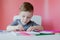 Portrait of cute kid boy at home making homework. Little concentrated child writing with colorful pencil, indoors. Elementary