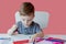 Portrait of cute kid boy at home making homework. Little concentrated child writing with colorful pencil, indoors. Elementary