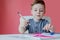 Portrait of cute kid boy at home making homework. Little concentrated child writing with colorful pencil, indoors. Elementary