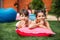 portrait of cute kids resting on inflatable mattress on green lawn on backyard of