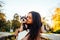 Portrait of a cute lady cuddling with a dog in the park on a background of autumn trees with yellow leaves and sunset. Leisure