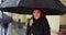 Portrait of cute Latina female holding black umbrella outside in the rain
