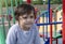 Portrait Cute litte boy sitting alone in playground, Candid Child boy looking out deep in through outdoors play area in sunny day