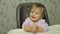Portrait of Cute little baby Caucasian girl sitting at the table