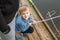 Portrait of cute little blond boy sitting on wooden pier near father. Adorable child having fun and smiling at lake or river shore